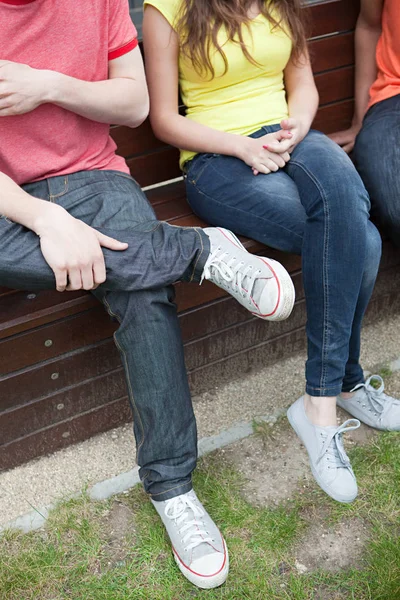 Junge Leute sitzen draußen auf Bank — Stockfoto