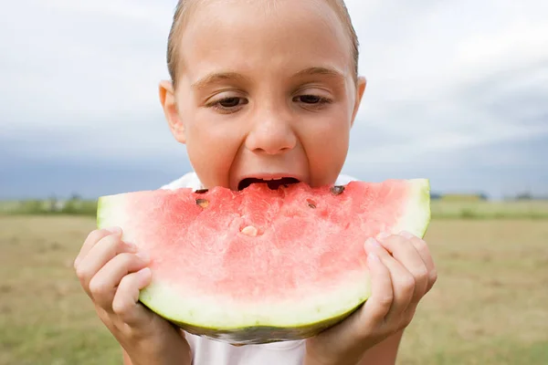 Menina tomando mordida de fatia de melancia — Fotografia de Stock