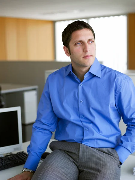 Young businessman sitting on desk — Stock Photo, Image