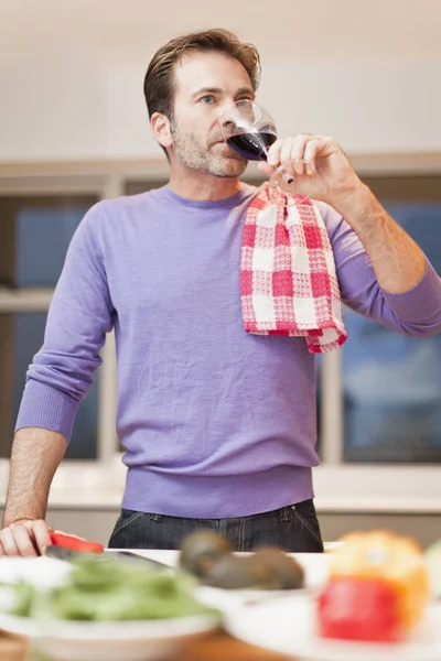 Чоловік п'є вино і готує вечерю — стокове фото