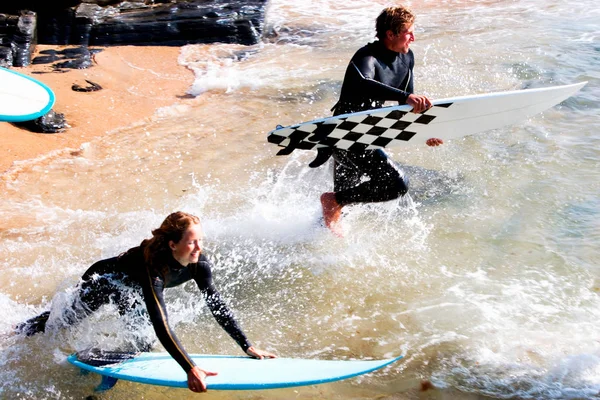 Couple avec planches de surf éclaboussures — Photo