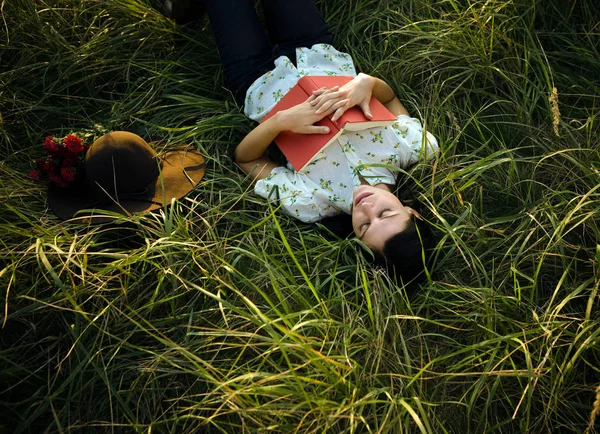 Mulher dormindo na grama com livro nas mãos — Fotografia de Stock