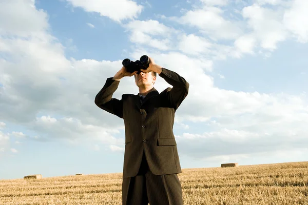 Man met verrekijker in veld — Stockfoto