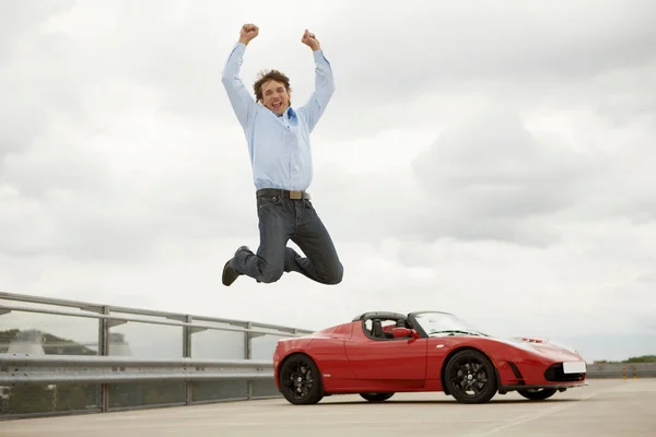 Людина перестрибуючи щасливо через електричний автомобіль — стокове фото