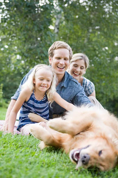 Family in park with golden retriever — Stock Photo, Image