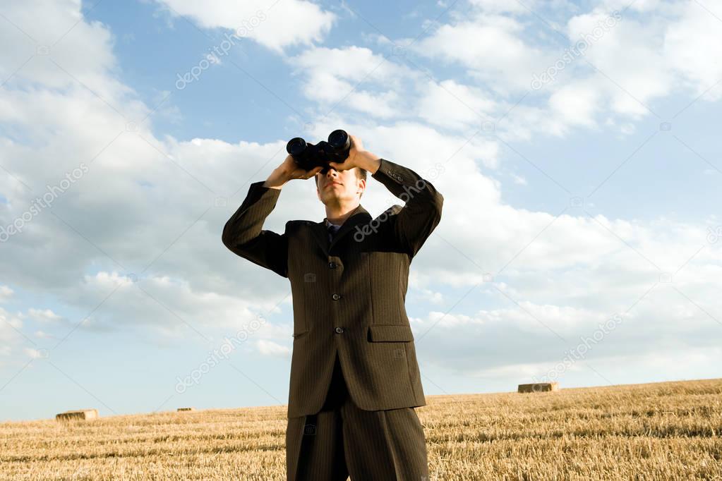 man using binoculars in field