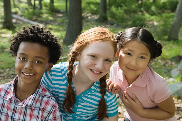 Kinder sitzen im Wald und schauen in die Kamera — Stockfoto