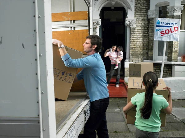 Family unpacking boxes from moving van