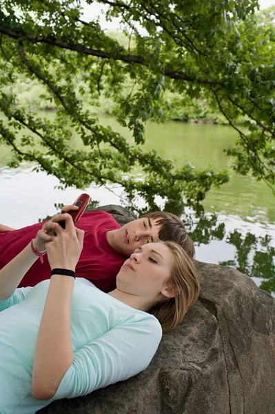 Couple using cellular telephone on rocks — Stock Photo, Image