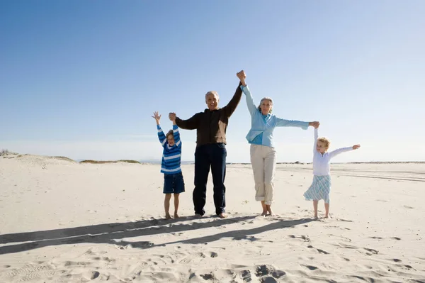 Großeltern spielen mit Enkeln am Strand — Stockfoto