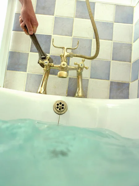 Hombre usando llave inglesa para arreglar la bañera —  Fotos de Stock