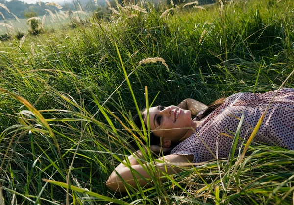 Jeune femme couchée dans l'herbe — Photo