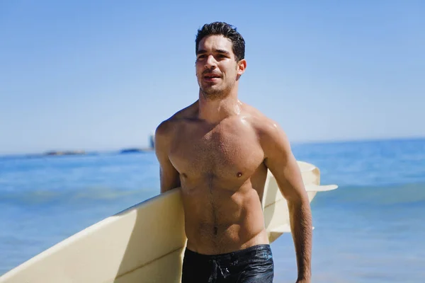 Mann trägt Surfbrett am Strand — Stockfoto