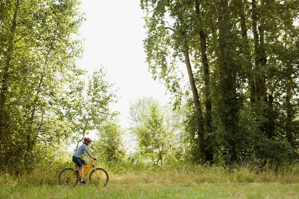 Kvinna Rider cykel genom äng — Stockfoto