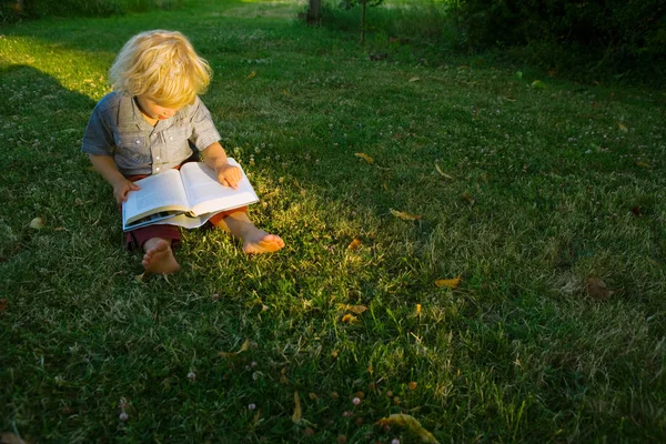 Kitap okumak ve dışarıda oturan çocuk — Stok fotoğraf