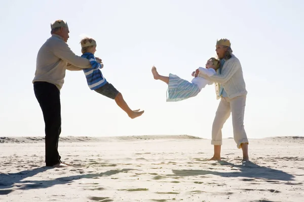 Großeltern spielen mit Enkeln am Strand — Stockfoto