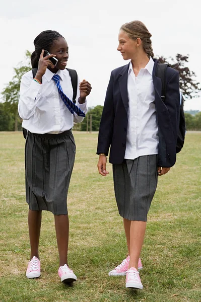 Schoolgirls walking with cellphone — Stock Photo, Image