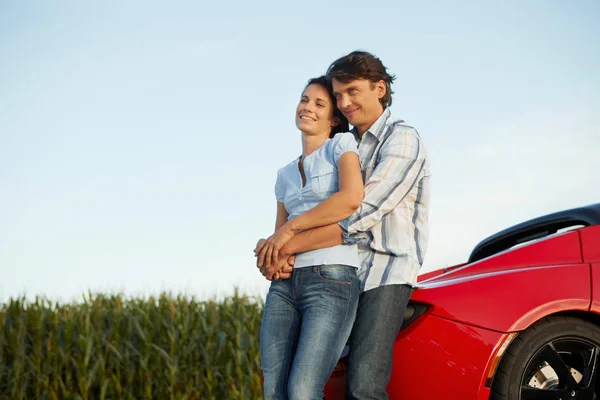 Pareja de pie junto a su coche eléctrico — Foto de Stock