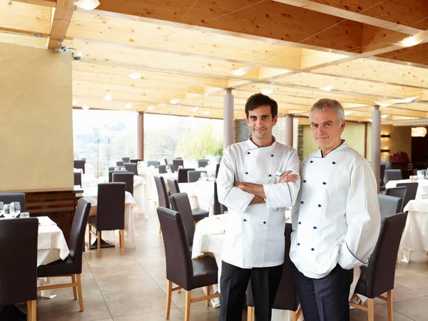Two proud chefs in a large restaurant