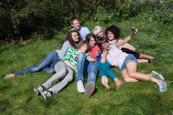 Amici sdraiati sull'erba prendendo selfie — Foto Stock