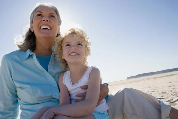 Бабуся і онука сидять на пляжі — стокове фото