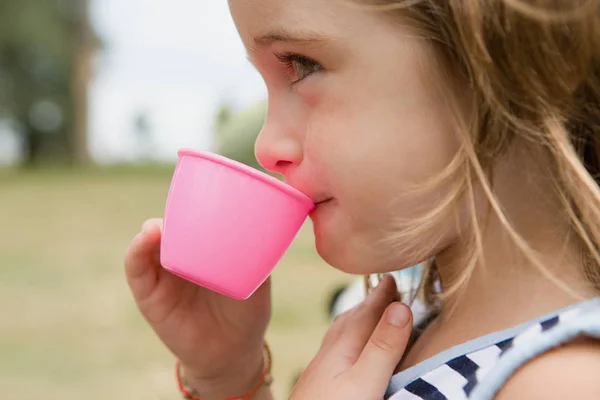 Ragazza che beve da tazza di plastica — Foto Stock