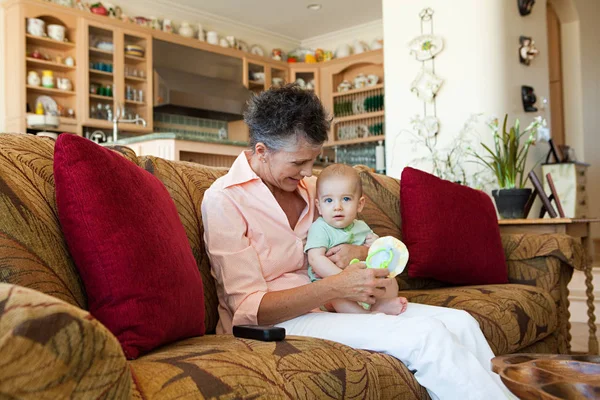 Mulher sentada no sofá com neto bebê — Fotografia de Stock