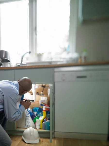 Человек ремонтирует сантехнику — стоковое фото