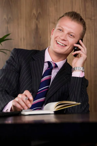 Uomo d'affari seduto alla scrivania e parlare al telefono — Foto Stock