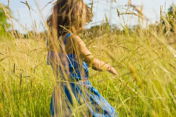Mädchen geht durch ein Feld aus langem Gras — Stockfoto