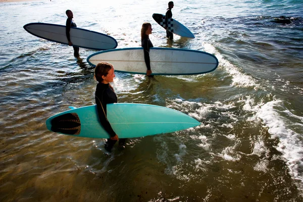 Quatre personnes debout avec des planches de surf — Photo