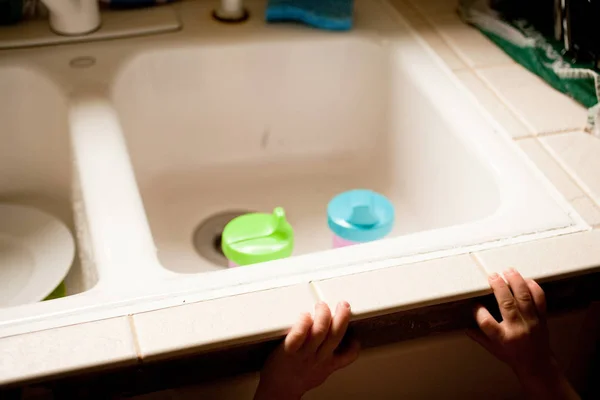 Child reaching towards kitchen sink — Stock Photo, Image
