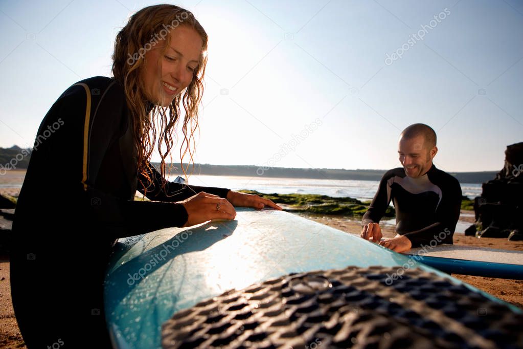 couple waxing surfboards