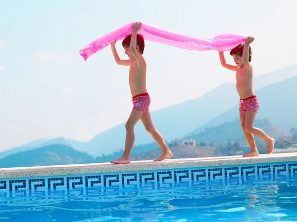 Dos hermanos llevando inflable en la piscina —  Fotos de Stock