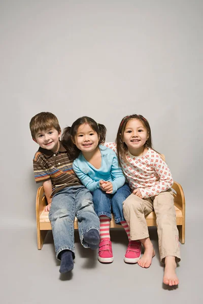 Дети сидят на скамейке — стоковое фото