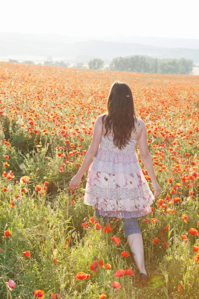Kvinna promenader i fält av blommor — Stockfoto