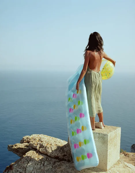Женщина, стоящая на скале и смотрящая на море — стоковое фото