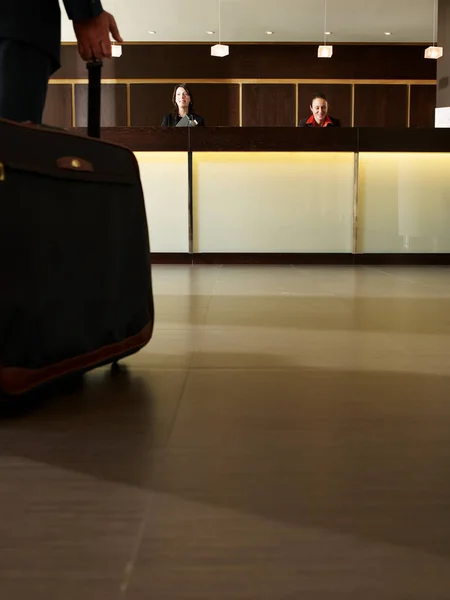 Człowiek z walizka w recepcji hotelu — Zdjęcie stockowe