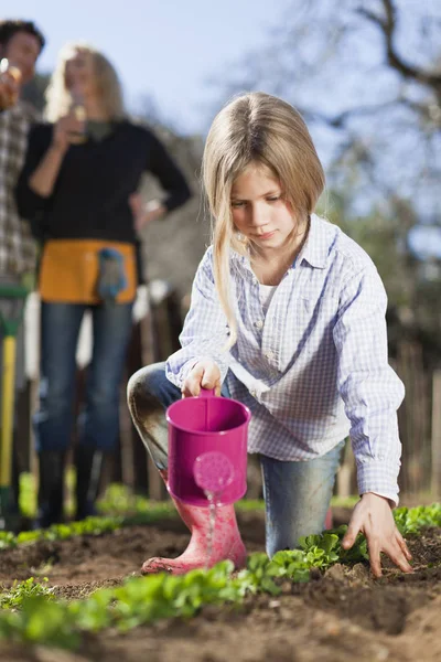 Mädchen gießt Pflanzen im Garten — Stockfoto