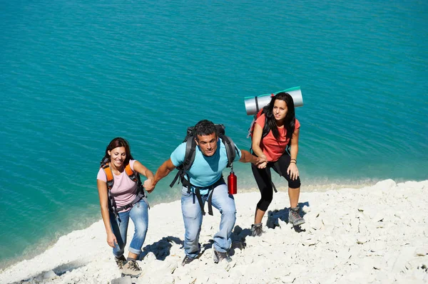 Três caminhantes caminhando com mochilas — Fotografia de Stock