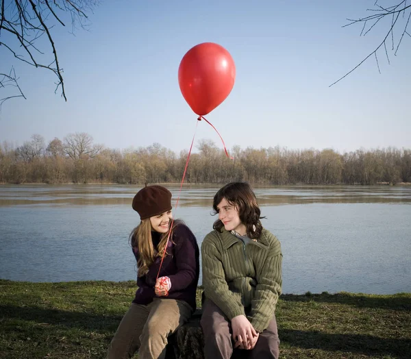 Poika ja tyttö pitelemässä ilmapalloa joella — kuvapankkivalokuva
