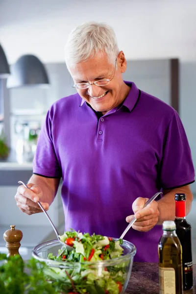 Старший чоловік готує салат — стокове фото