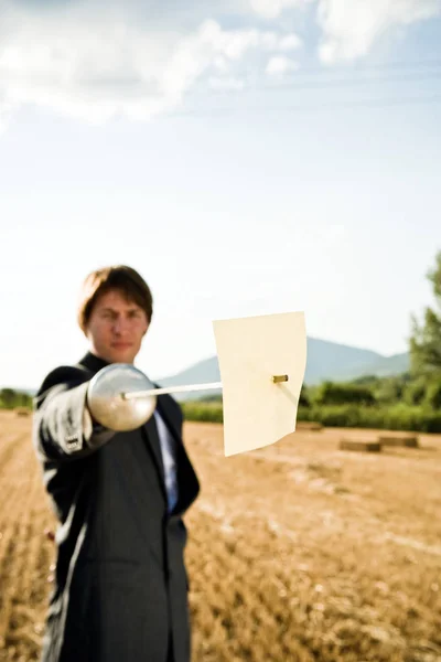 Empresário piercing papel com espada de esgrima — Fotografia de Stock