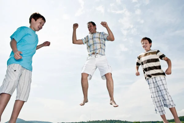 Padre y dos hijos saltando —  Fotos de Stock