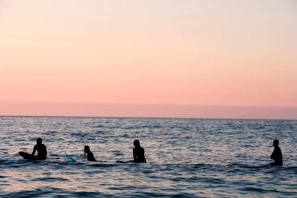 Quatre personnes assises sur des planches de surf — Photo