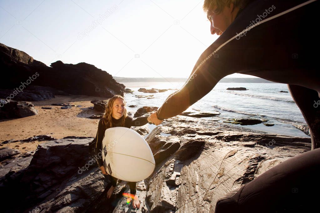 Man helping woman with surfboard