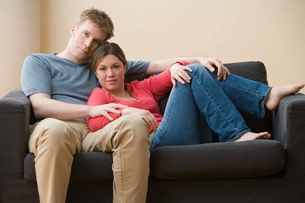 Pareja en sofá mirando a la cámara — Foto de Stock