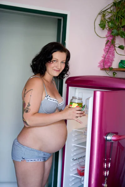 Hamile kadın mutfakta turşu ile ayakta — Stok fotoğraf