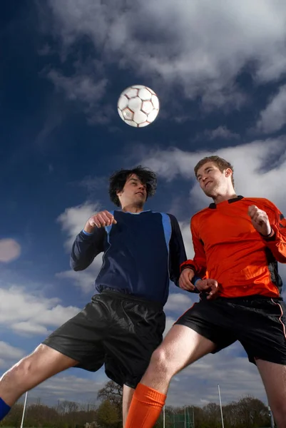 İki futbolcular futbol topu için atlama — Stok fotoğraf