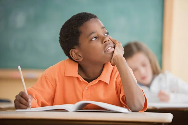 Boy daydreaming over opened textbook — Stock Photo, Image